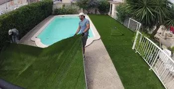 Déroulage du gazon synthétique le long de la piscine