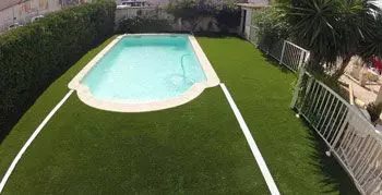 Gazon synthétique posé autour d'une piscine sur sol dur